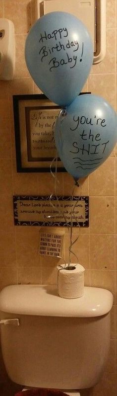 two balloons are floating over the toilet in this bathroom with congratulations written on it's side