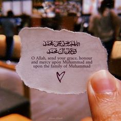 a person holding up a piece of paper with an arabic quote on it in front of them