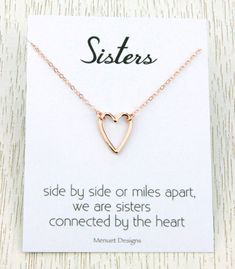 a gold heart necklace on a card saying sisters side by side or miles apart, we are sisters connected by the heart