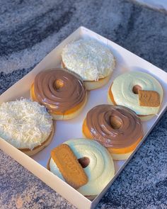 six donuts in a box with frosting and toppings