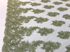 an embroidered lace with green flowers on white fabric