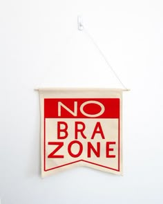 a red and white sign that says no bra zone hanging on a wall in a room