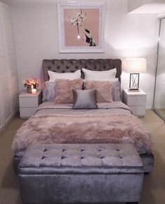 a bedroom with a bed, ottoman and pictures on the wall above it that is decorated in pink and grey tones