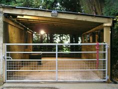 a metal gate is open to allow people to enter the area where there are trees in the background