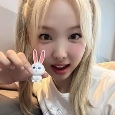 a young woman holding up a small toy rabbit