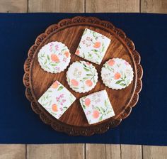 four pieces of cake sitting on top of a wooden plate next to a blue table cloth