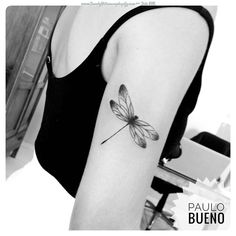 a black and white photo of a woman's arm with a dragonfly tattoo on it