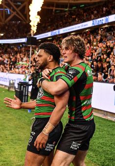 two rugby players are hugging each other in front of an audience at a sporting event