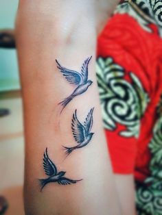 a woman's arm with three birds tattoo on the left side of her arm