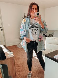 a woman taking a selfie with her phone in the living room while wearing black and white shoes