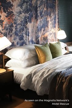 a bed with white sheets and pillows in front of a wallpapered headboard