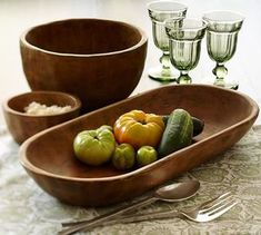 there is a wooden tray with different types of vegetables in it and silverware on the table