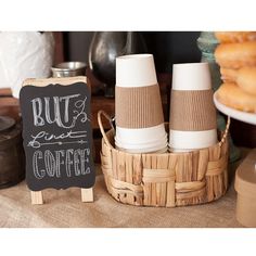 coffee cups are sitting in a basket next to a chalkboard sign that says, but don't forget coffee