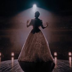 a woman in a white dress is standing on a stage with candles lit up behind her