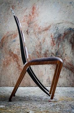 a wooden chair sitting on top of a carpeted floor next to a stone wall