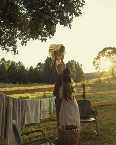 two women are hanging out in the yard and one is holding something up to her head