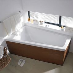 a bath tub sitting next to a window with towels hanging on the wall above it