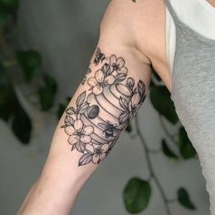 a woman with a tattoo on her arm holding a cupcake and flowers in it