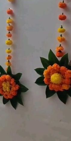 two orange and yellow flowers are attached to the wall