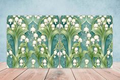 a wooden table topped with a green and white wallpaper covered in lily of the valley flowers