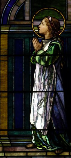 a woman standing in front of a stained glass window