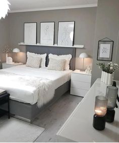 a white bed sitting in a bedroom next to two lamps and pictures on the wall