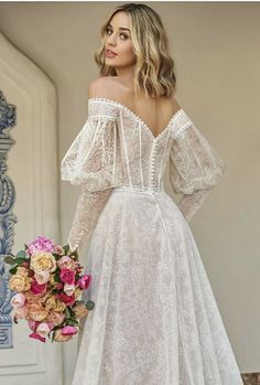 a woman in a white wedding dress with flowers on the side and her back to the camera