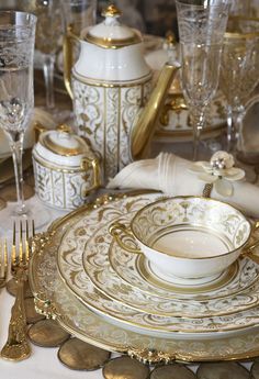 a fancy table setting with gold and white dishes