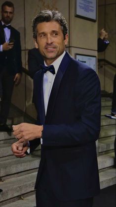 a man in a tuxedo standing on some steps