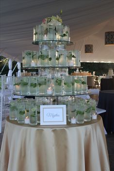 there is a table that has many jars on it with flowers in them and candles inside