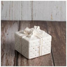 a small white gift box with a bow on the top sitting on a wooden table