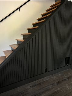 a cat sitting on top of a wooden stair case next to a bannister