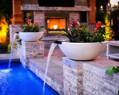 a large bowl with water coming out of it next to a fire place and pool