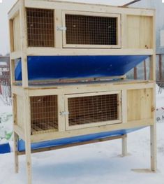 a large wooden bird cage sitting on top of snow covered ground