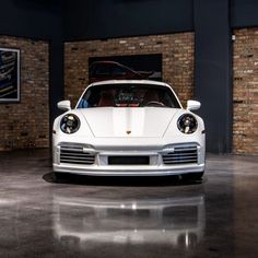 a white sports car parked in front of a brick wall with exposed lighting on it