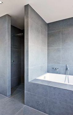 a bathroom with gray walls and tile flooring is shown in this image, there are two shower heads on either side of the bathtub