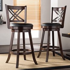 two wooden barstools with black leather seats in front of a white wall and beige carpet