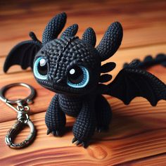 a small black dragon keychain sitting on top of a wooden table next to a pair of scissors