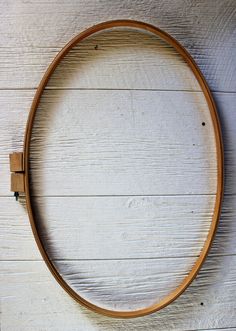 a circular wooden frame on a white wood wall with an iron hook in the middle