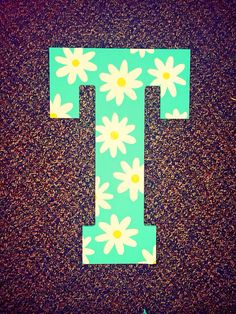 the letter t is made out of paper with daisies and flowers painted on it