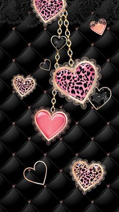 some pink and black heart shaped keychais hanging from a chain on a black background