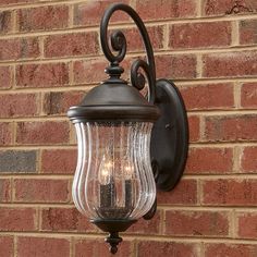 a wall mounted light on the side of a brick building with two candles in it