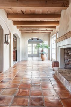 an empty hallway with brick floors and stone fireplace in the center, surrounded by potted plants