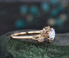 a gold ring with an opal and amethorate in the center on top of a green rock