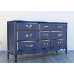 a blue dresser with gold handles and drawers