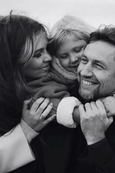 a black and white photo of a man with two children on his shoulders, smiling at the camera