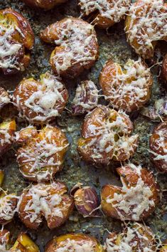 baked potatoes covered in cheese and herbs on a baking sheet, ready to be eaten