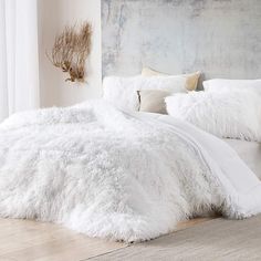 a bed with white fluffy blankets and pillows