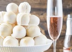 a white bowl filled with marshmallows next to a glass of champagne