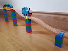 there is a toy train set on the wooden floor next to two blocks that look like tracks